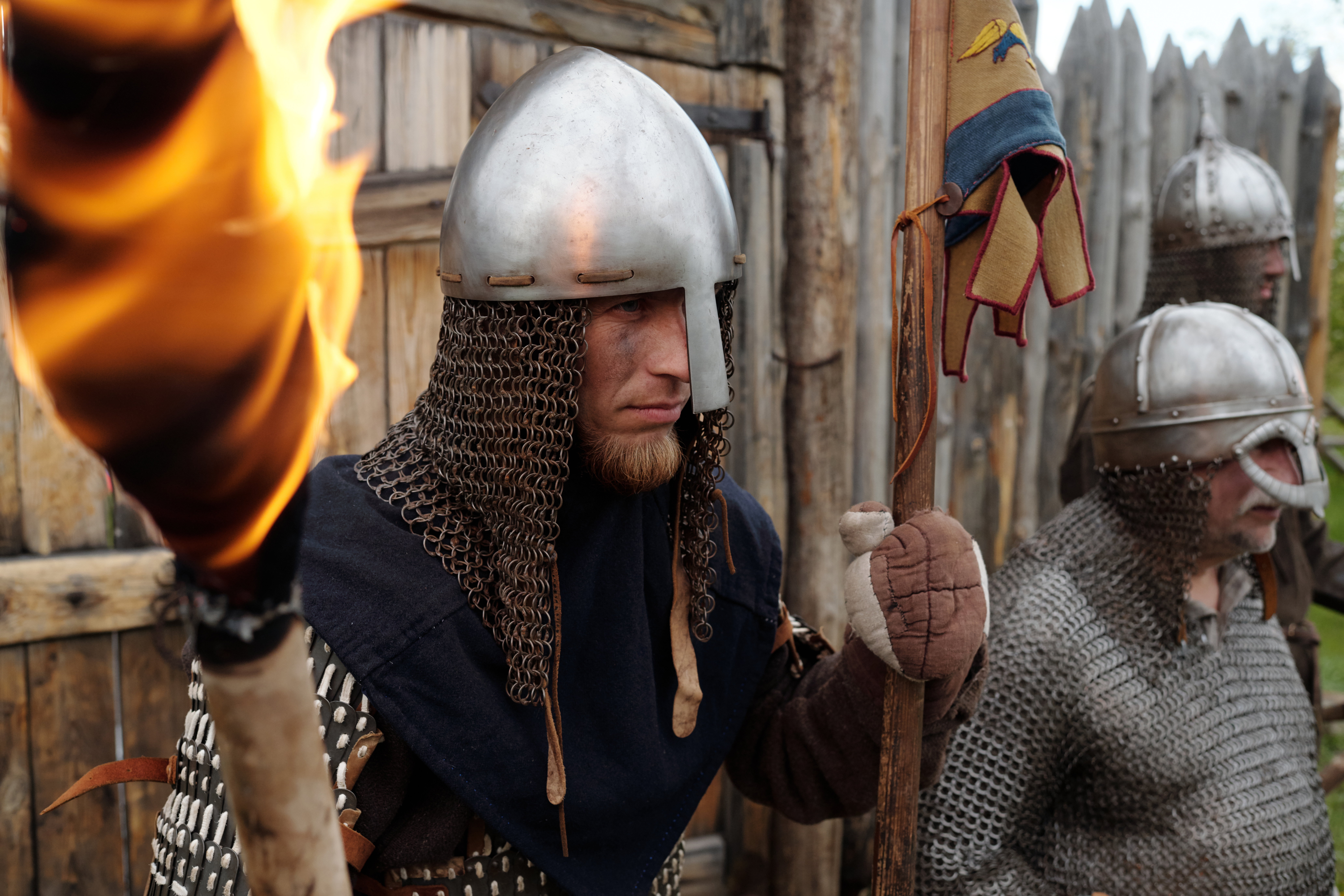 Im März 2025 NEU im Shop: Die große Wikinger-Themenwelt, mit neuen Produkten, Aktionen und News zur Wikingerzeit! Teaser für unseren neuen Wikinger Shop | Gerüsteter Wikingertrupp vor Festung mit grimmigem Blick und Fackel in der Hand